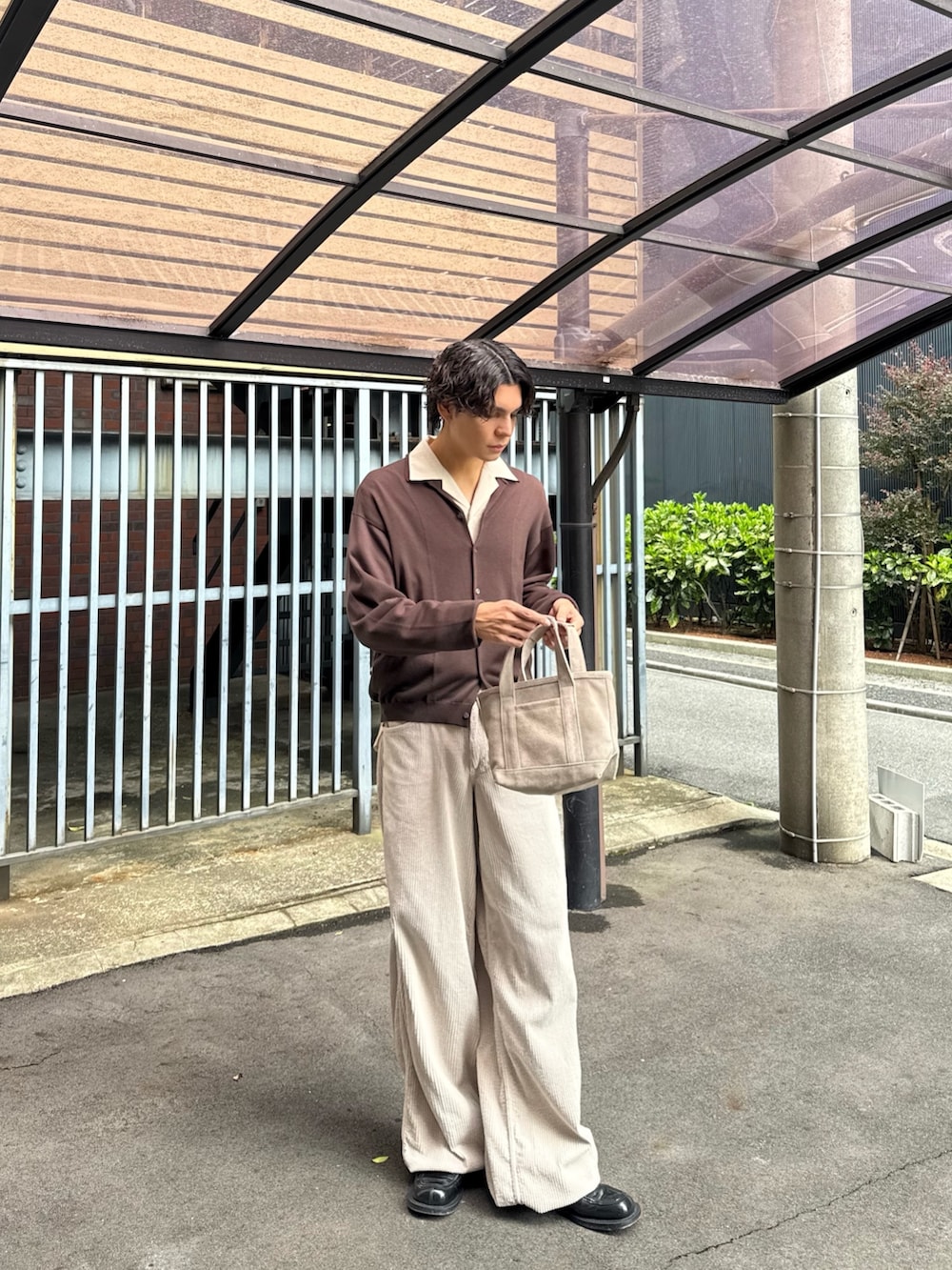 ブラウン系のニット/セーター、ベージュ系のハンドバッグ、ベージュ系のその他パンツを着用したメンズの春コーディネートの4枚目の写真