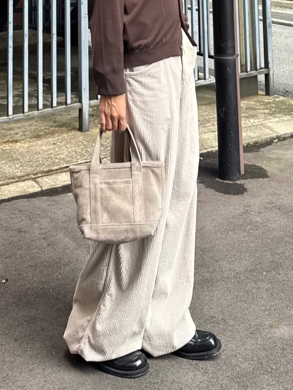 ブラウン系のニット/セーター、ベージュ系のハンドバッグ、ベージュ系のその他パンツを着用したメンズの春コーディネートの3枚目の写真