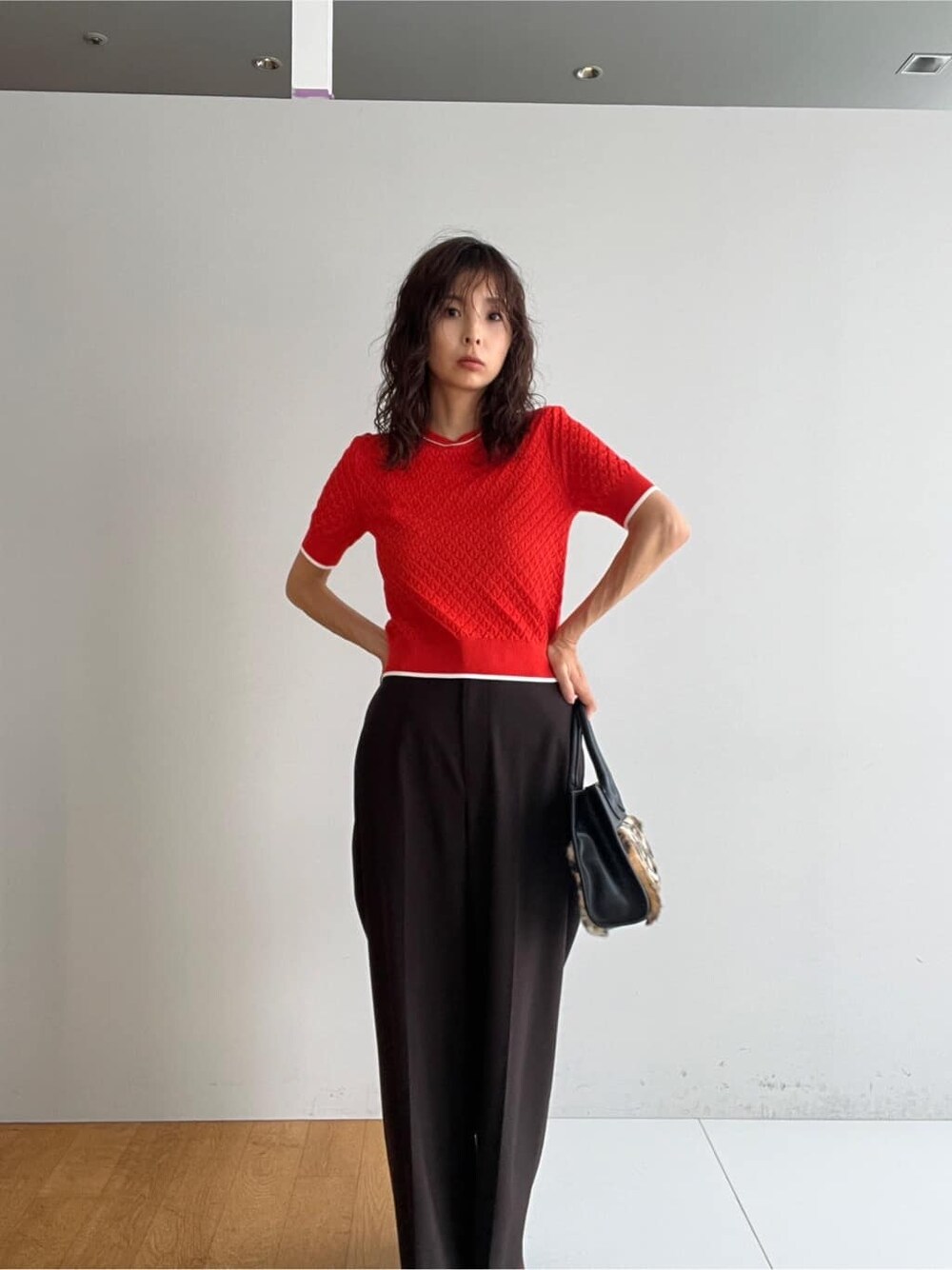 オレンジ系のニット/セーター、ブラウン系のその他パンツ、ベージュ系のトートバッグを着用したレディースの秋コーディネートの5枚目の写真