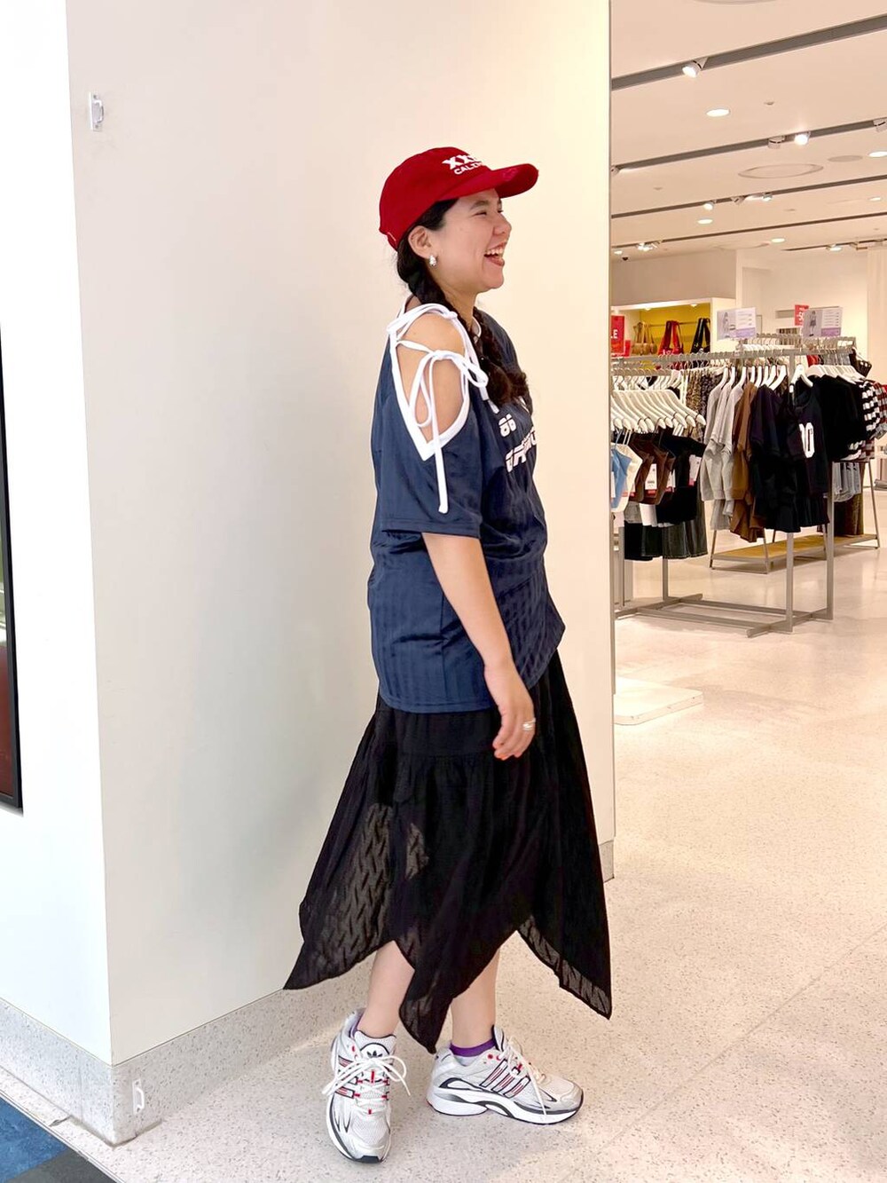 ブルー系のワンピース、ブラック系のスカート、レッド系のキャップを着用したレディースの夏コーディネートの2枚目の写真