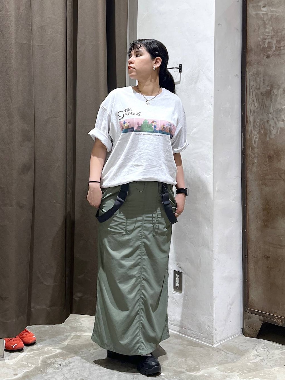 ブラック系のスニーカー、グリーン系のジャンパースカート、ベージュ系のTシャツ/カットソーを着用したレディースの夏コーディネートの3枚目の写真