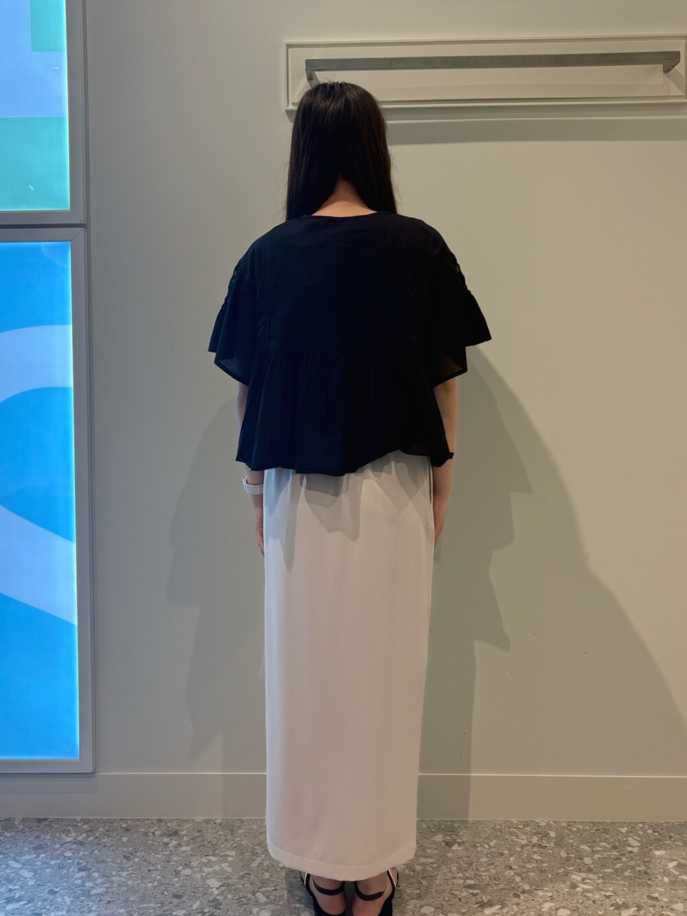 ブラック系のシャツ/ブラウス、ベージュ系のスカート、ブラック系のサンダルを着用したレディースの夏コーディネートの3枚目の写真