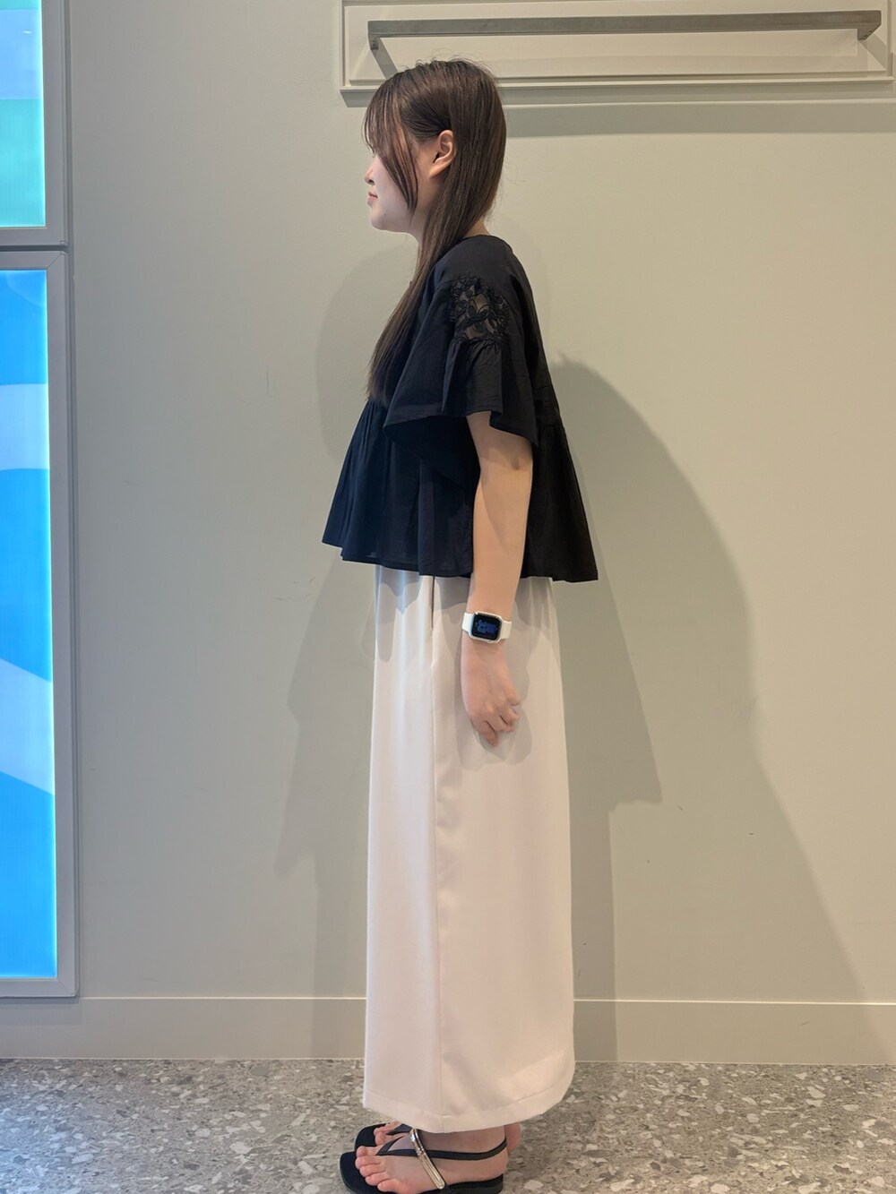 ブラック系のシャツ/ブラウス、ベージュ系のスカート、ブラック系のサンダルを着用したレディースの夏コーディネートの2枚目の写真