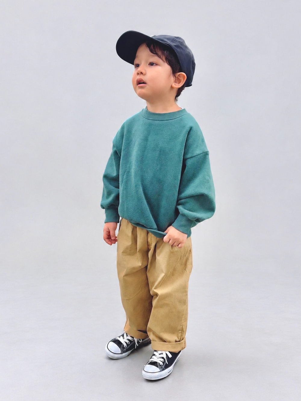 ベージュ系のチノパンツ、グリーン系のスウェット、ブラック系のスニーカーを着用したキッズの秋コーディネートの2枚目の写真