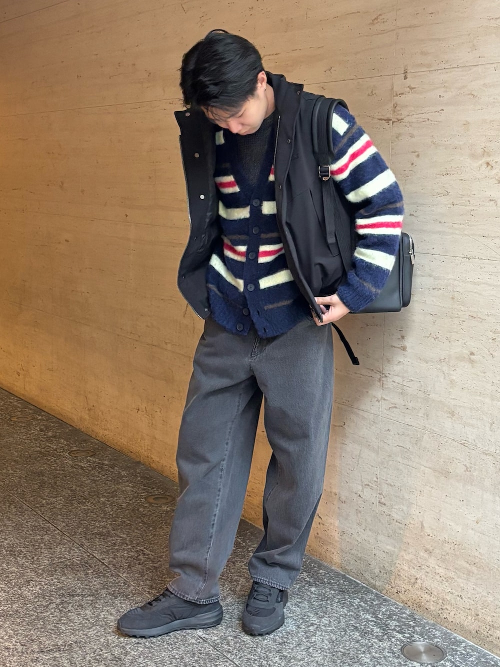 ブラック系のダウンベスト、ブルー系のカーディガン/ボレロ、ブラック系のデニムパンツを着用したメンズの冬コーディネートの2枚目の写真