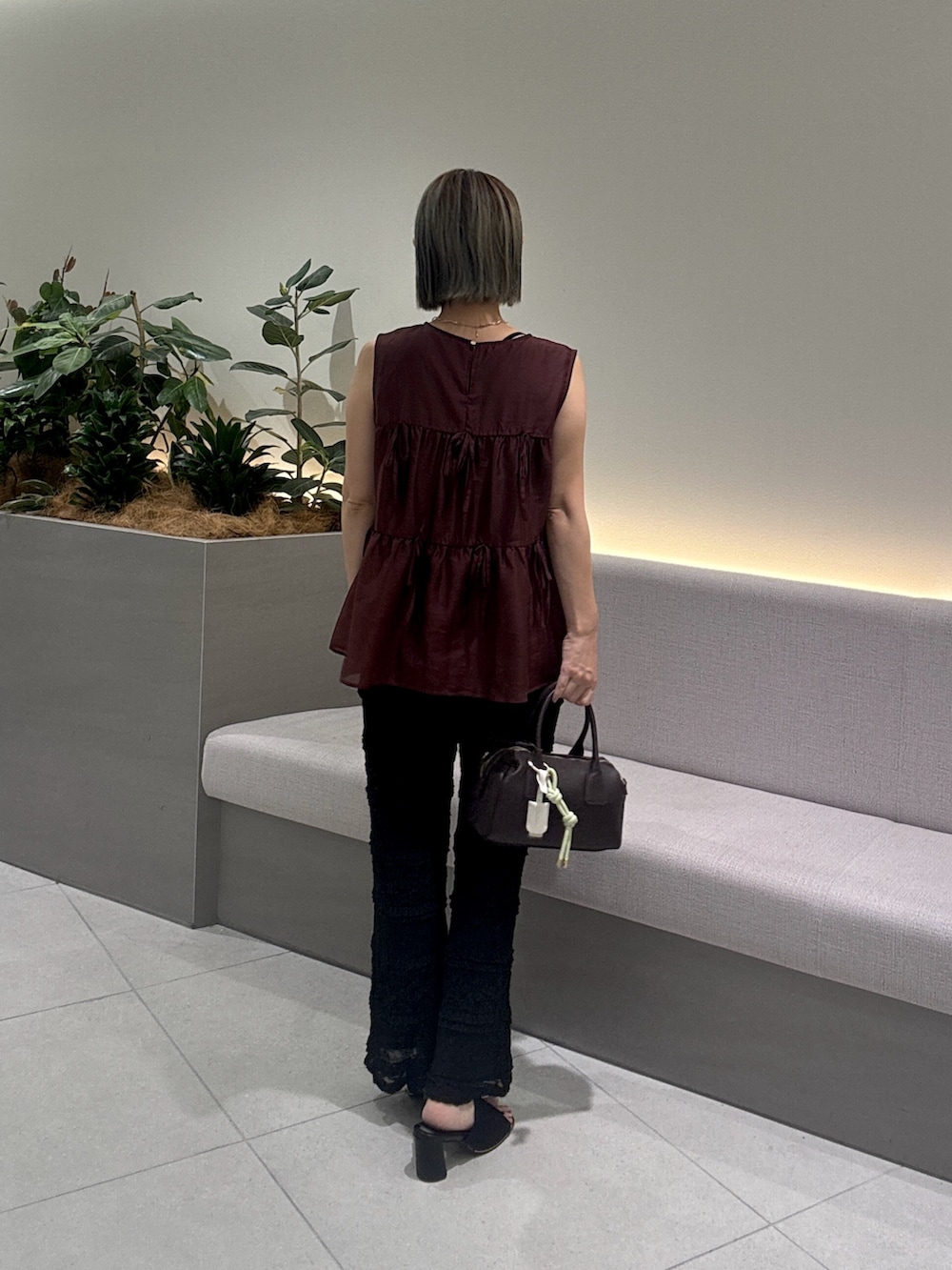 レッド系のシャツ/ブラウス、ブラック系のその他パンツ、ブラウン系のボストンバッグを着用したレディースの夏コーディネートの6枚目の写真