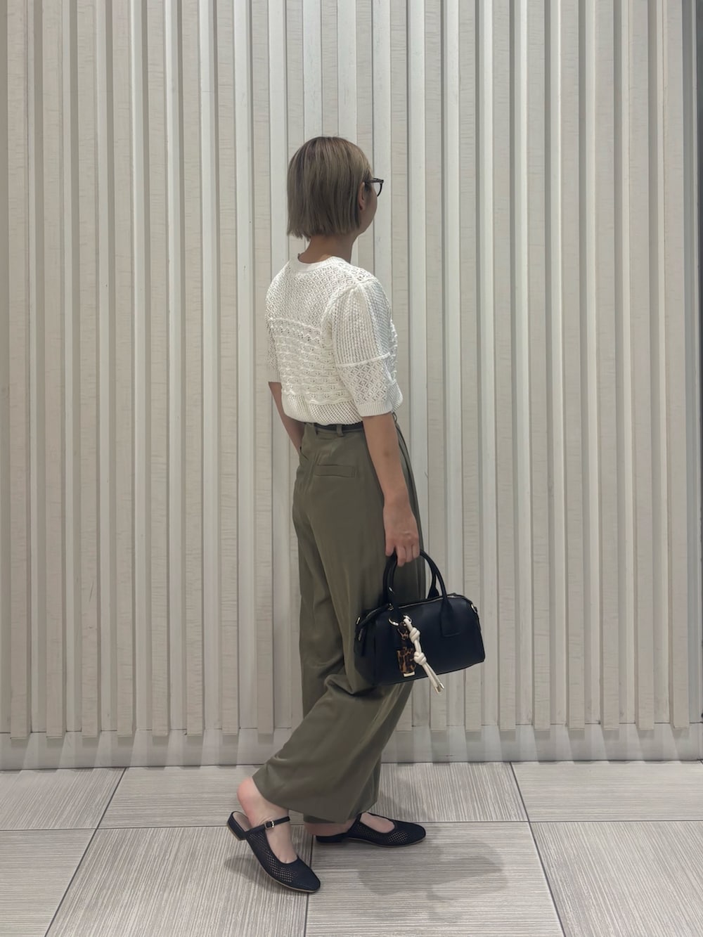 グリーン系のその他パンツ、ホワイト系のニット/セーター、ブラック系のボストンバッグを着用したレディースの夏コーディネートの3枚目の写真