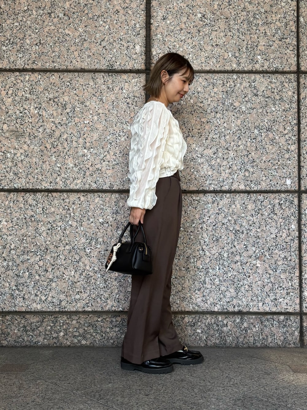 ブラウン系のその他パンツ、ホワイト系のTシャツ/カットソー、ブラック系のボストンバッグを着用したレディースの秋コーディネートの3枚目の写真