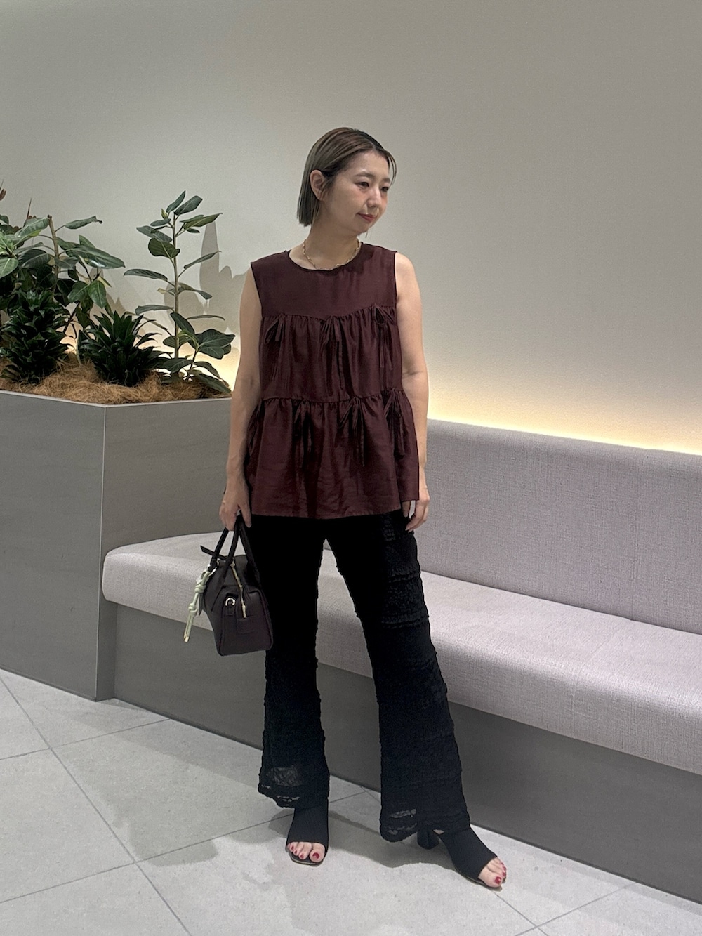 レッド系のシャツ/ブラウス、ブラック系のその他パンツ、ブラウン系のボストンバッグを着用したレディースの夏コーディネートの2枚目の写真