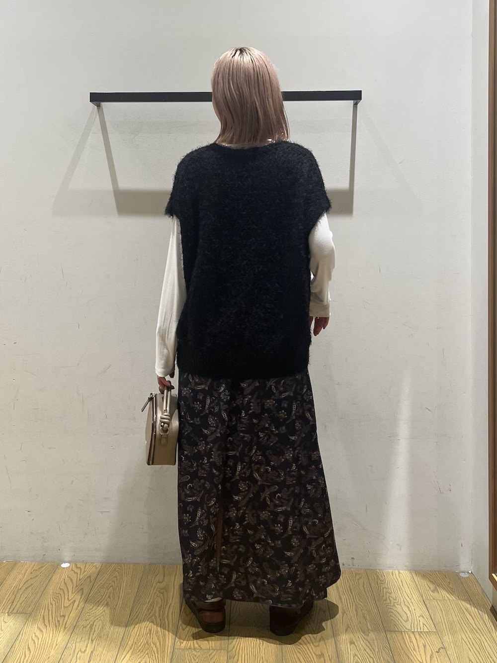 ブラック系のニット/セーター、ホワイト系のTシャツ/カットソー、ブルー系のスカートを着用したレディースの秋コーディネートの4枚目の写真