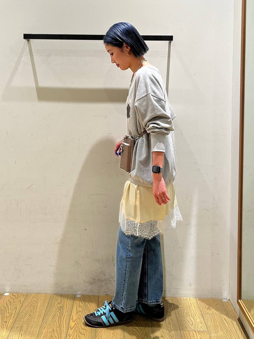 ブルー系のデニムパンツ、ベージュ系のワンピース、グレー系のスウェットを着用したレディースの冬コーディネートの2枚目の写真