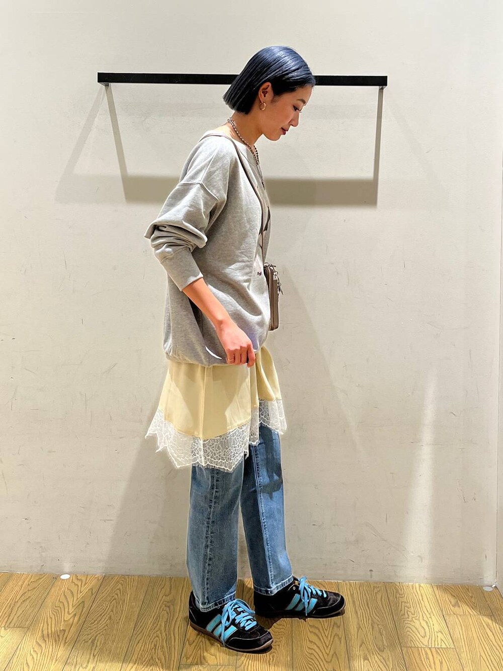 ブルー系のデニムパンツ、ベージュ系のワンピース、グレー系のスウェットを着用したレディースの冬コーディネートの3枚目の写真