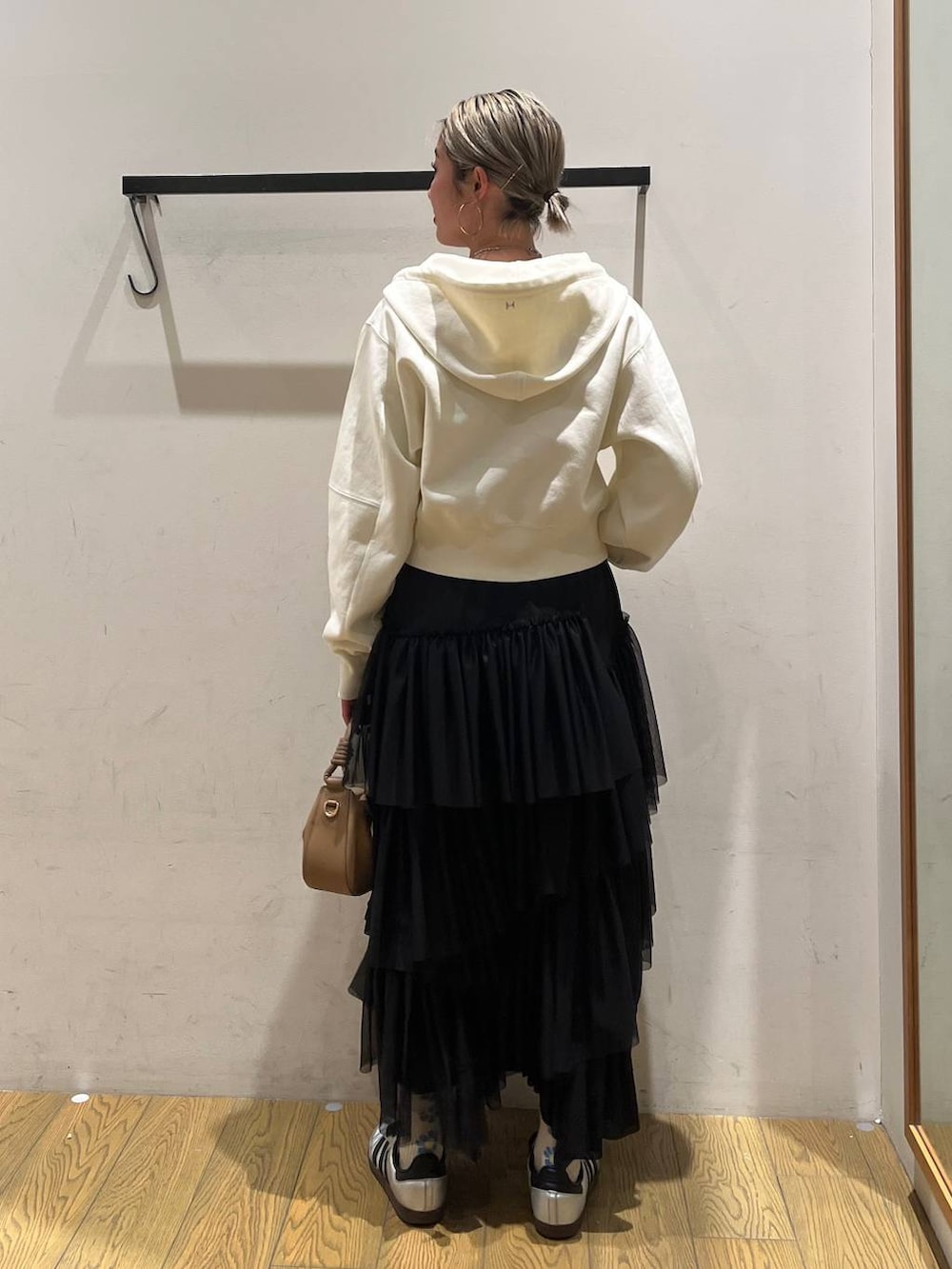 ベージュ系のハンドバッグ、ブラック系のスカート、ベージュ系のパーカーを着用したレディースの春コーディネートの4枚目の写真