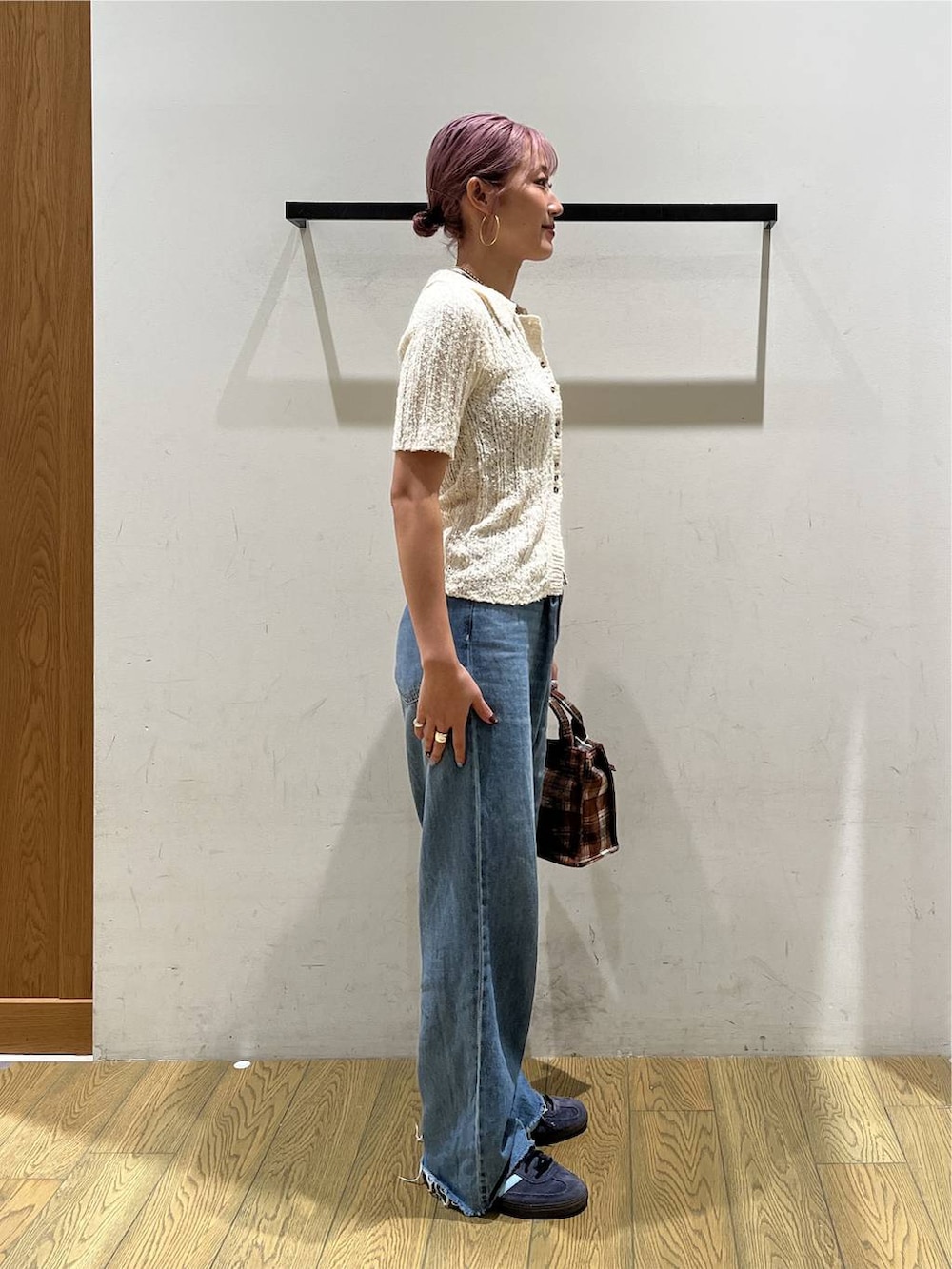 ブルー系のデニムパンツ、オレンジ系のトートバッグ、ホワイト系のニット/セーターを着用したレディースの夏コーディネートの2枚目の写真