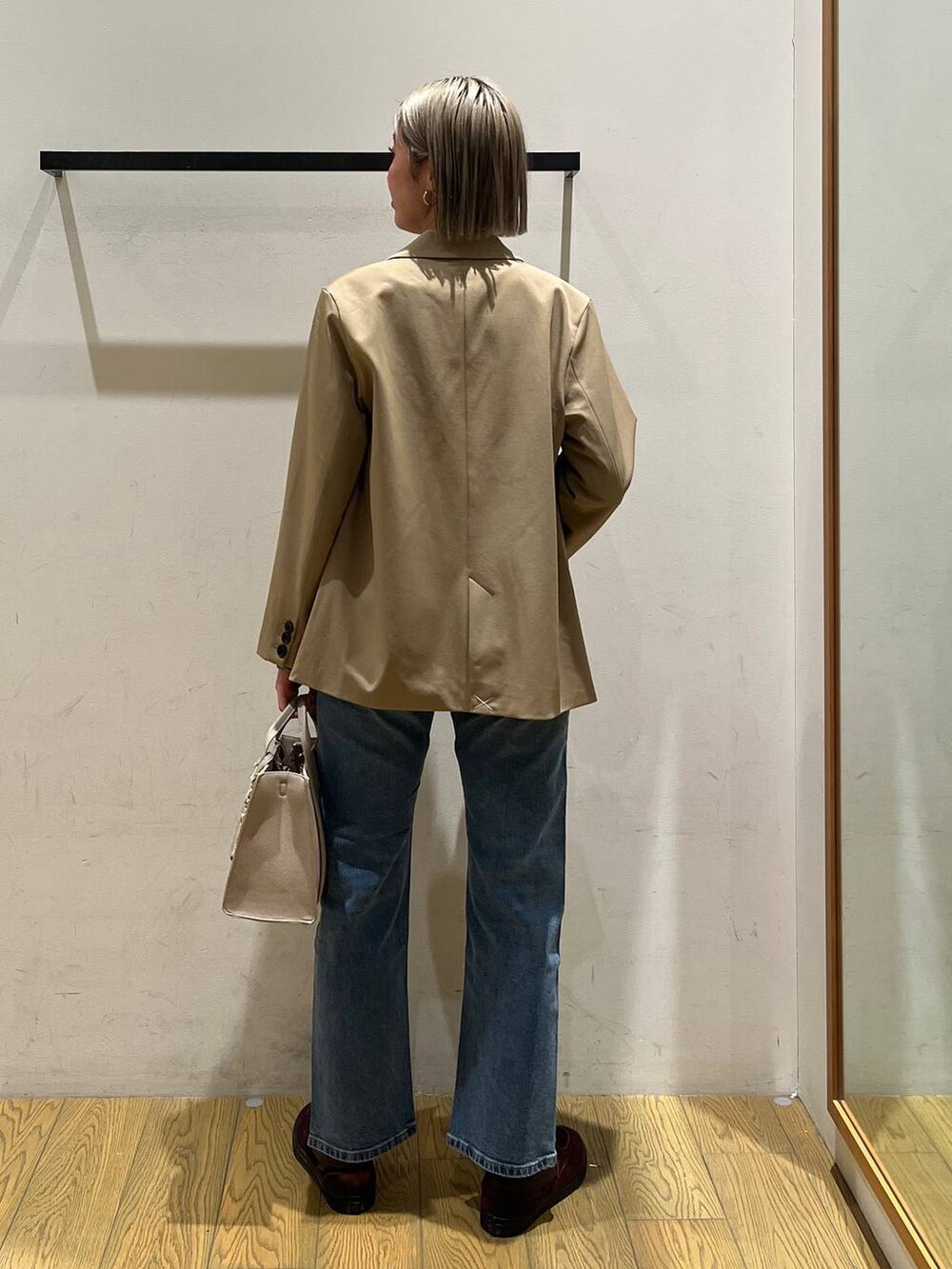 ベージュ系のハンドバッグ、ベージュ系のテーラードジャケット、ブルー系のデニムパンツを着用したレディースの冬コーディネートの4枚目の写真