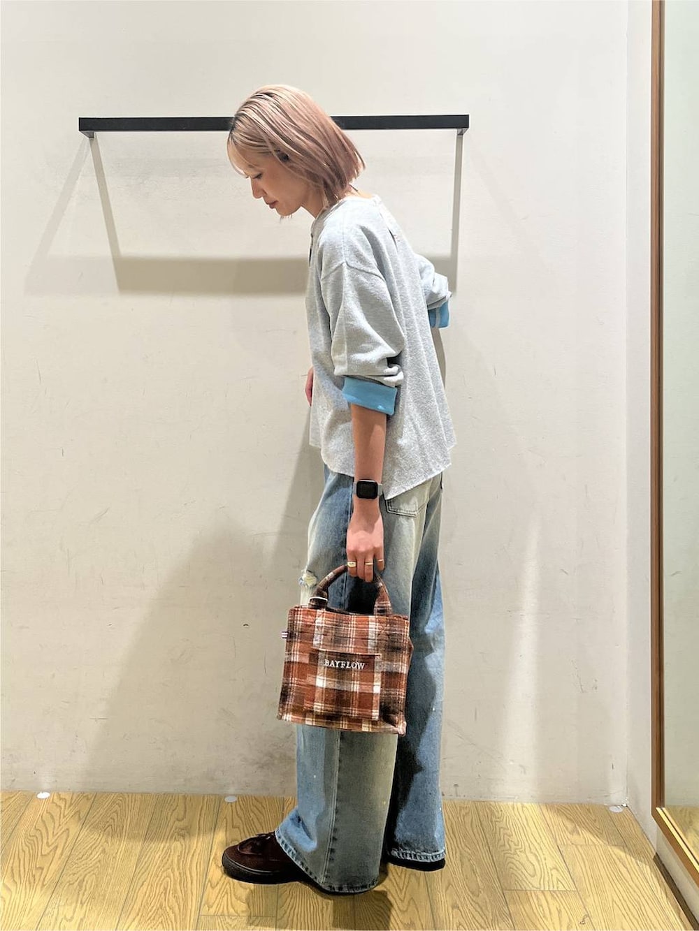 オレンジ系のトートバッグ、ブルー系のデニムパンツ、グレー系のニット/セーターを着用したレディースの秋コーディネートの2枚目の写真
