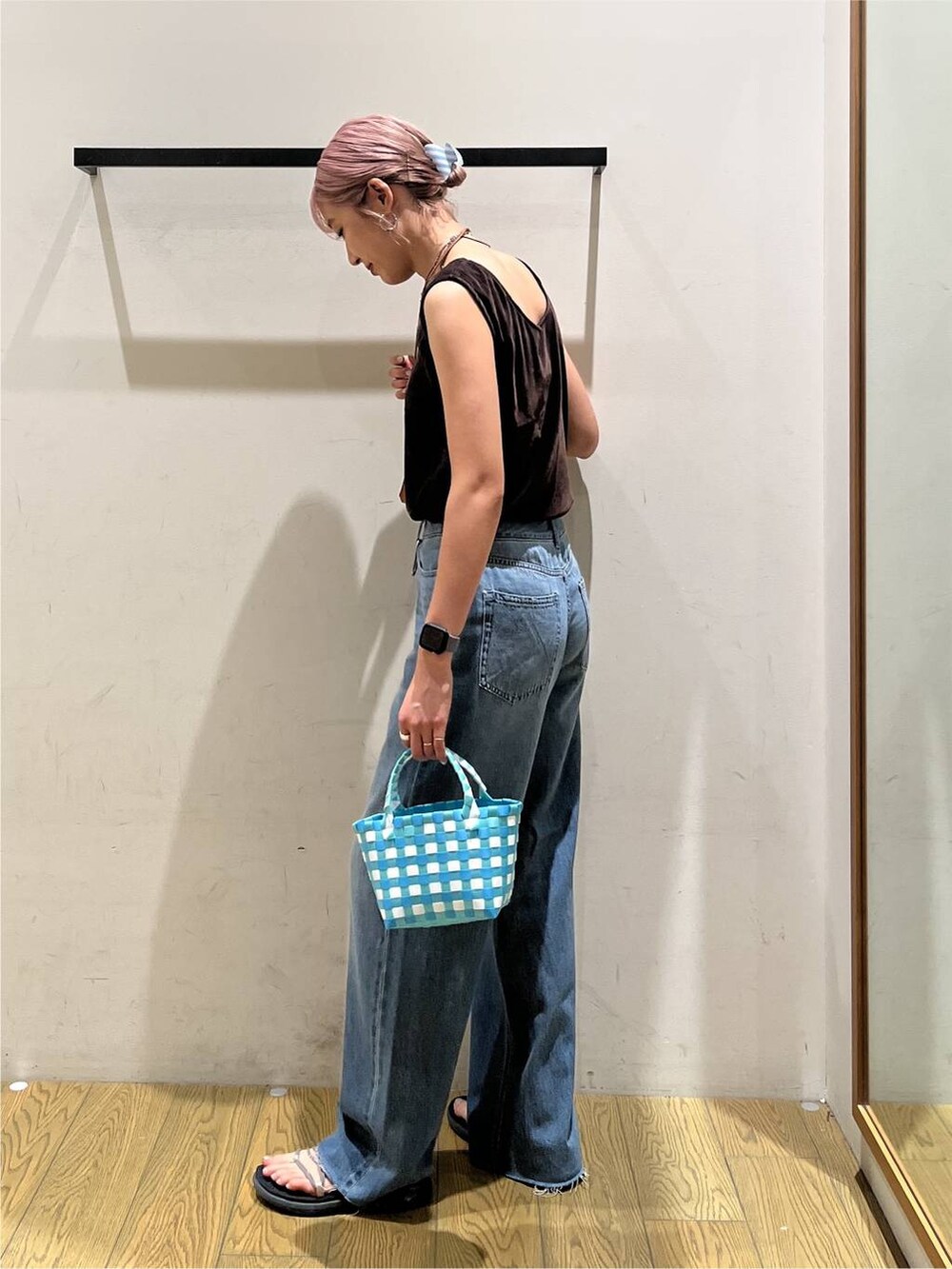 ブルー系のデニムパンツ、ブルー系のハンドバッグ、ブラウン系のネックレスを着用したレディースの夏コーディネートの3枚目の写真