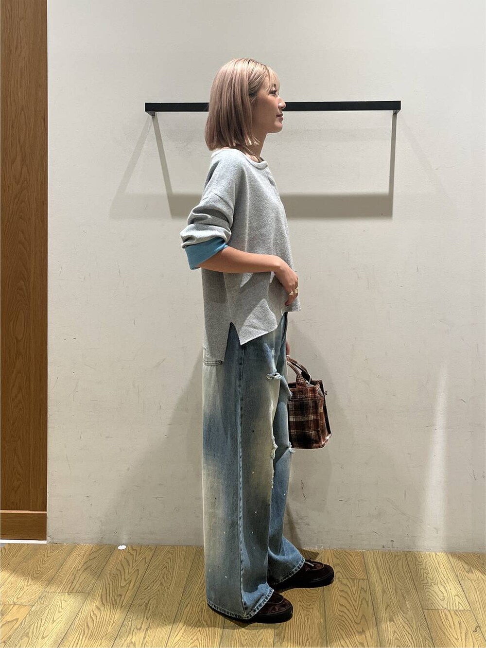 オレンジ系のトートバッグ、ブルー系のデニムパンツ、グレー系のニット/セーターを着用したレディースの秋コーディネートの3枚目の写真