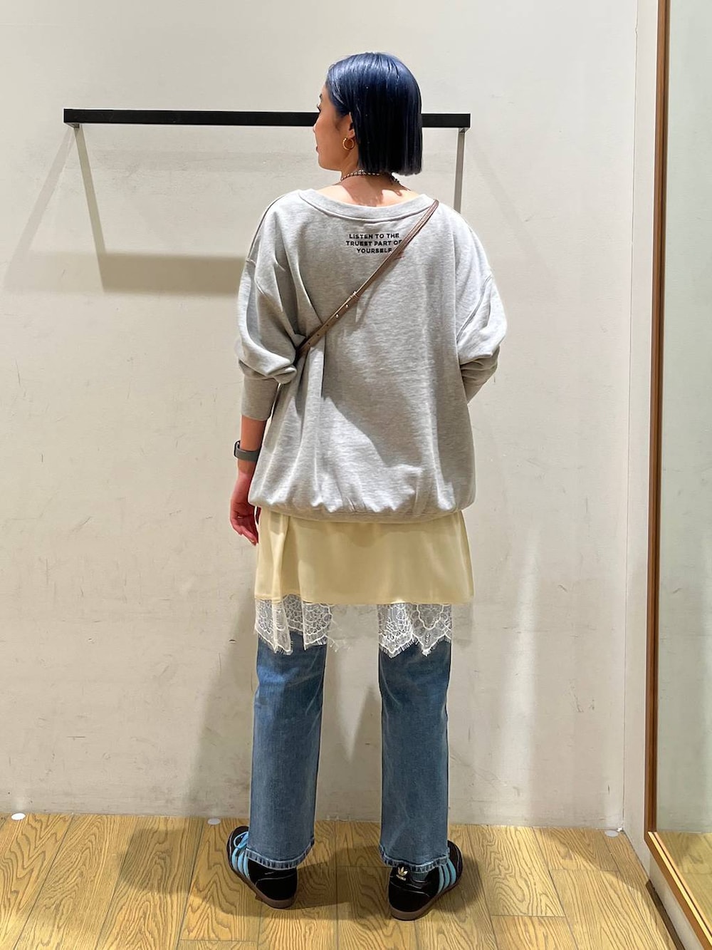 ブルー系のデニムパンツ、ベージュ系のワンピース、グレー系のスウェットを着用したレディースの冬コーディネートの4枚目の写真