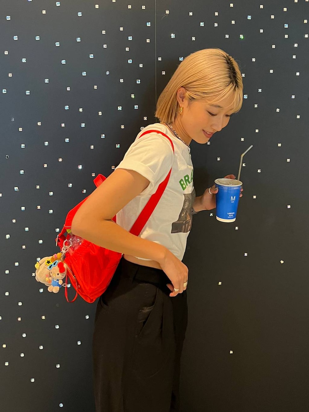レッド系のバックパック/リュック、ブラック系のチノパンツ、グリーン系のTシャツ/カットソーを着用したレディースの夏コーディネートの2枚目の写真