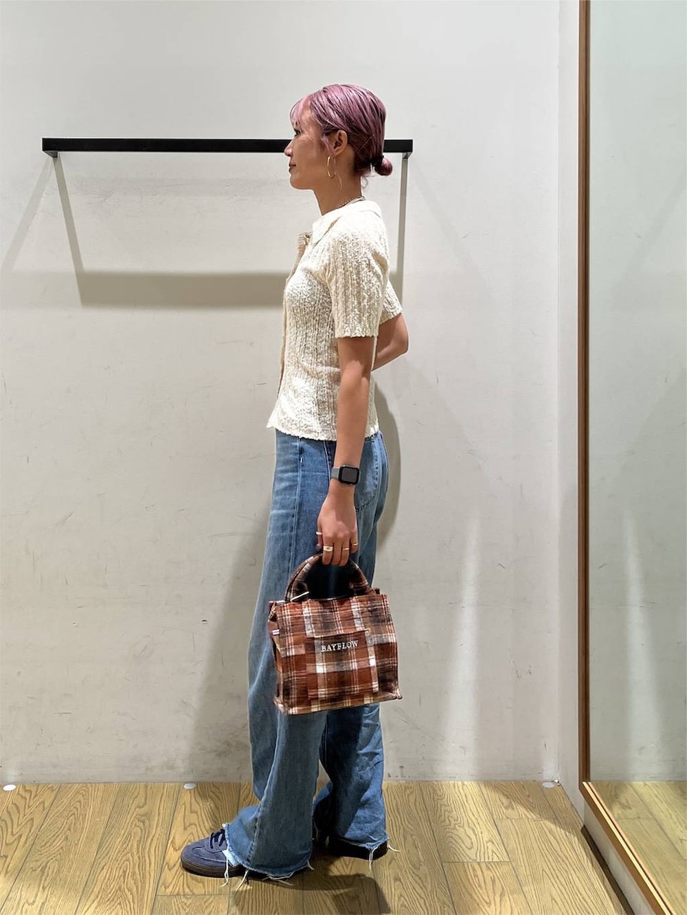 ブルー系のデニムパンツ、オレンジ系のトートバッグ、ホワイト系のニット/セーターを着用したレディースの夏コーディネートの3枚目の写真