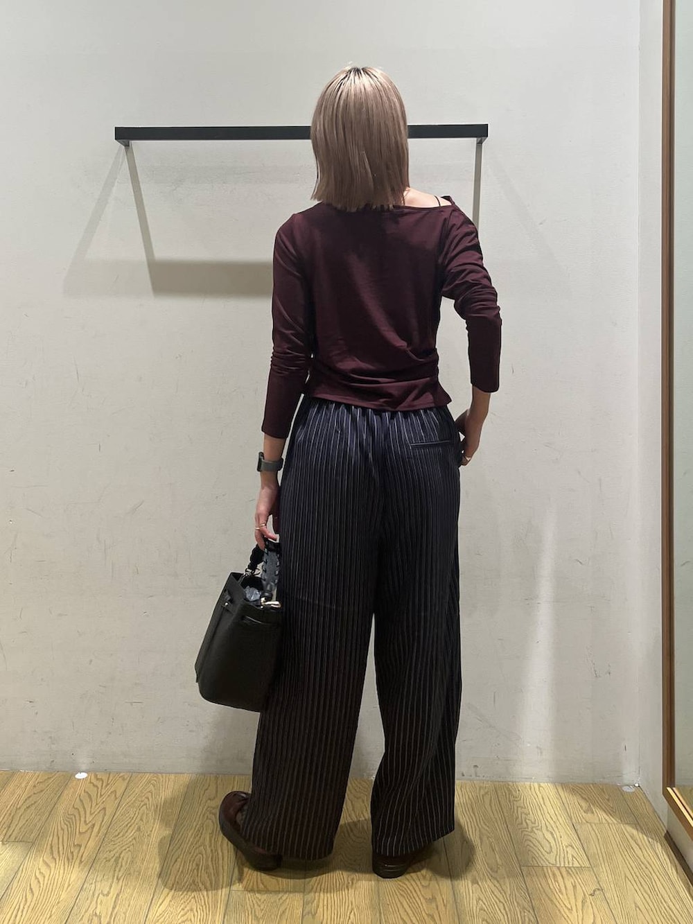 ブルー系のスラックス、レッド系のTシャツ/カットソー、ブラック系のショルダーバッグを着用したレディースの秋コーディネートの4枚目の写真