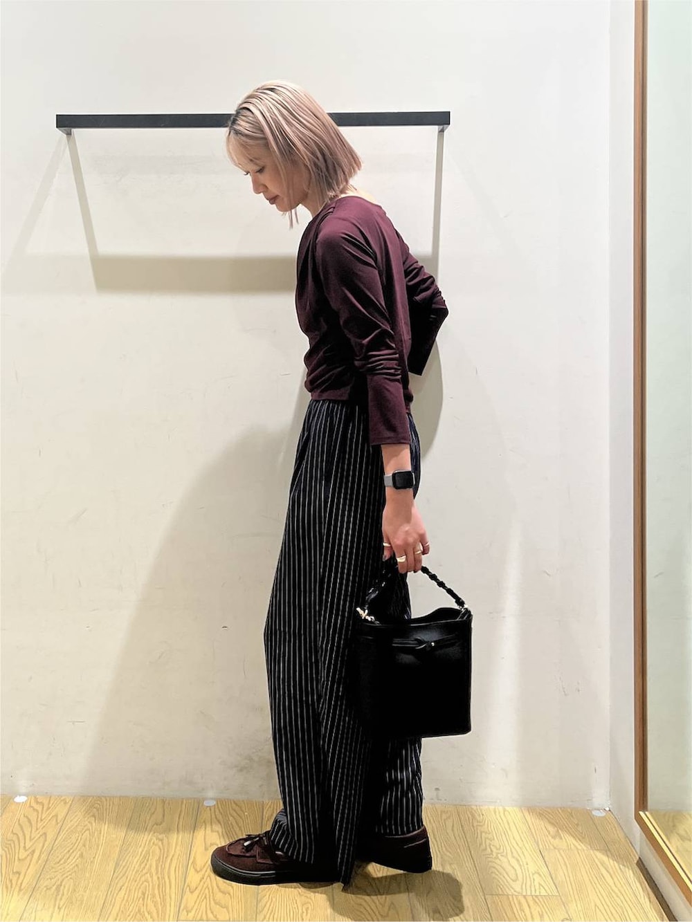 ブルー系のスラックス、レッド系のTシャツ/カットソー、ブラック系のショルダーバッグを着用したレディースの秋コーディネートの3枚目の写真