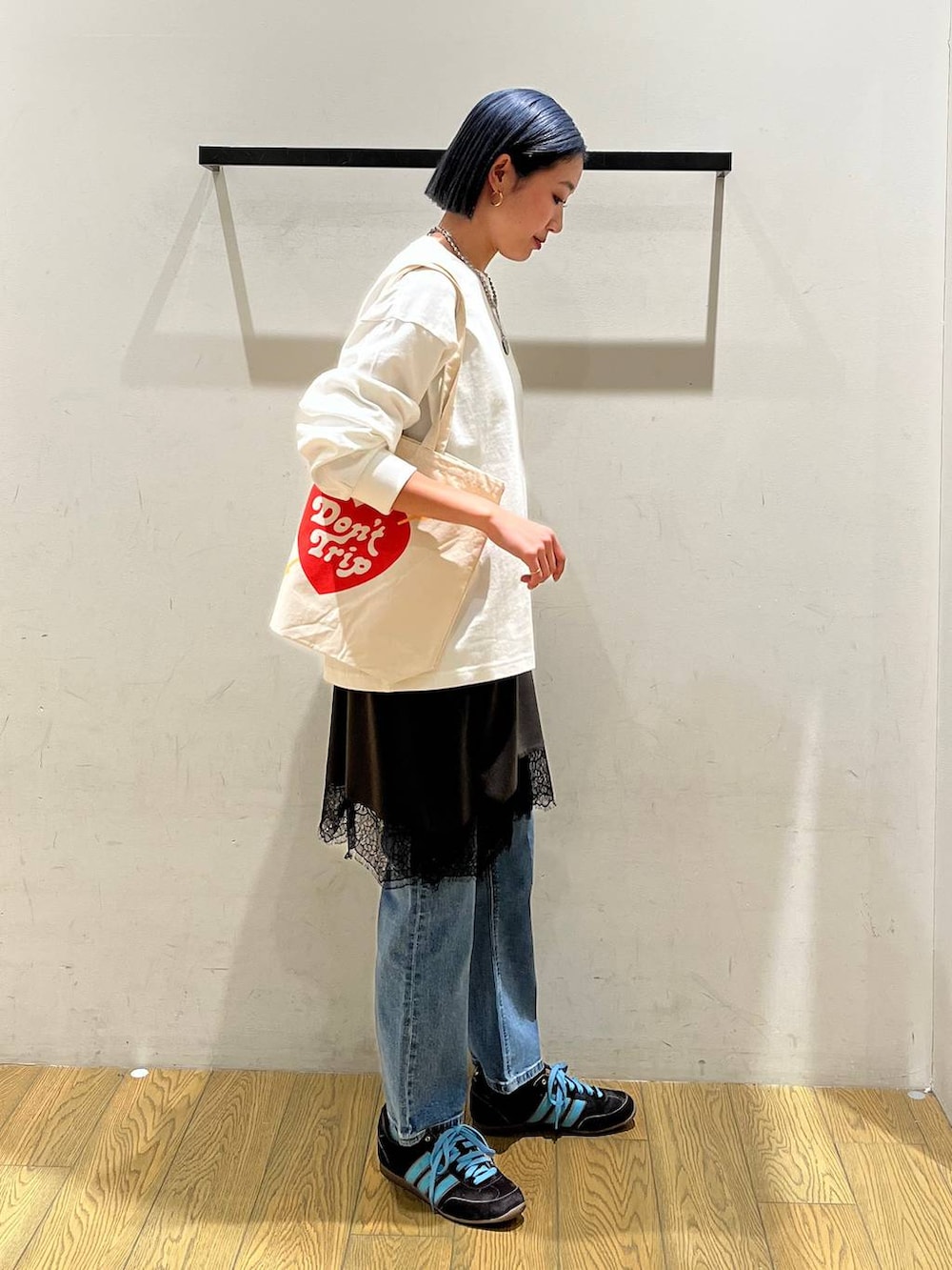 ブルー系のデニムパンツ、グレー系のワンピース、ベージュ系のトートバッグを着用したレディースの冬コーディネートの2枚目の写真