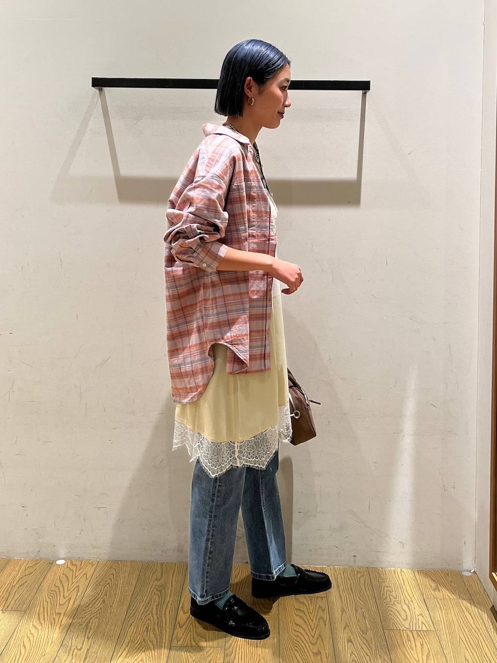 オレンジ系のシャツ/ブラウス、ブラウン系のハンドバッグ、ブラック系のローファーを着用したレディースの冬コーディネートの3枚目の写真