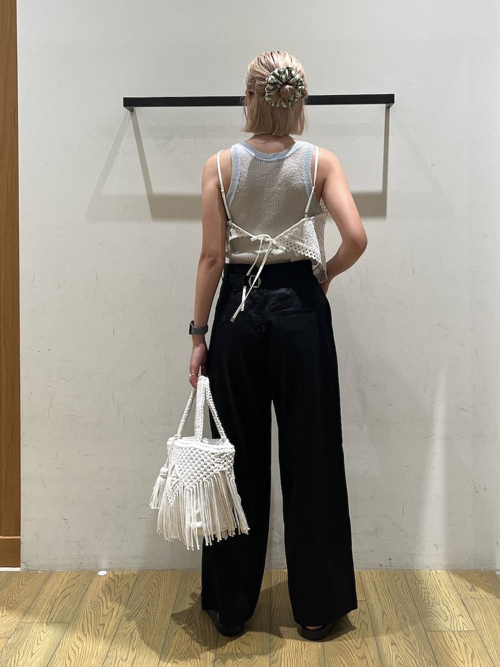 ベージュ系のトートバッグ、ブラック系のチノパンツ、ホワイト系のキャミソールを着用したレディースの夏コーディネートの4枚目の写真