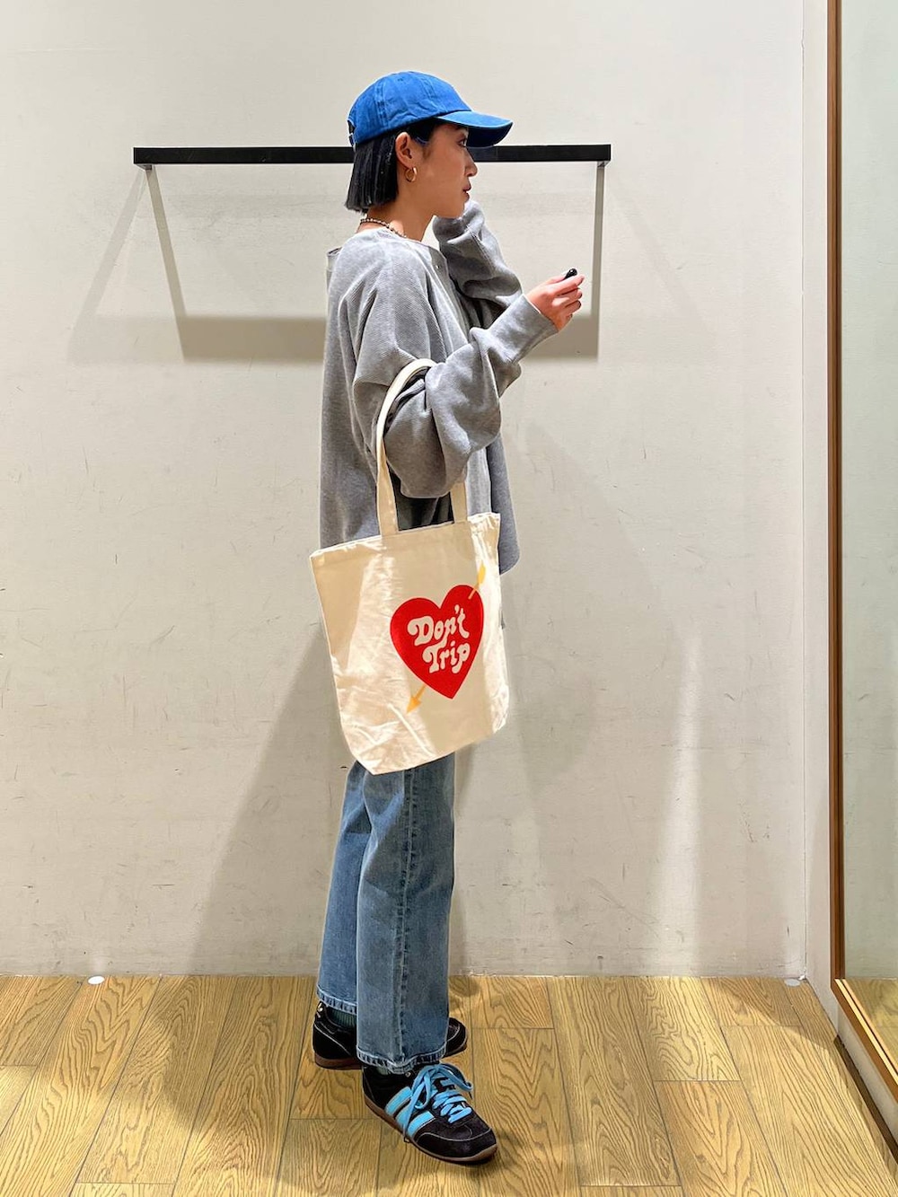 グレー系のカーディガン/ボレロ、ブルー系のデニムパンツ、ベージュ系のトートバッグを着用したレディースの冬コーディネートの3枚目の写真