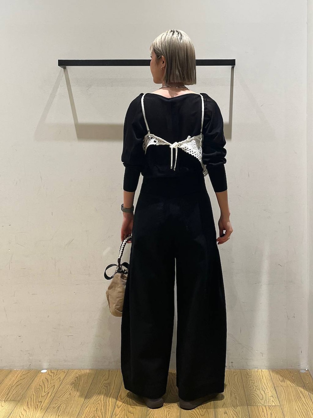 ベージュ系のショルダーバッグ、ブラック系のニット/セーター、ブラック系のチノパンツを着用したレディースの春コーディネートの4枚目の写真