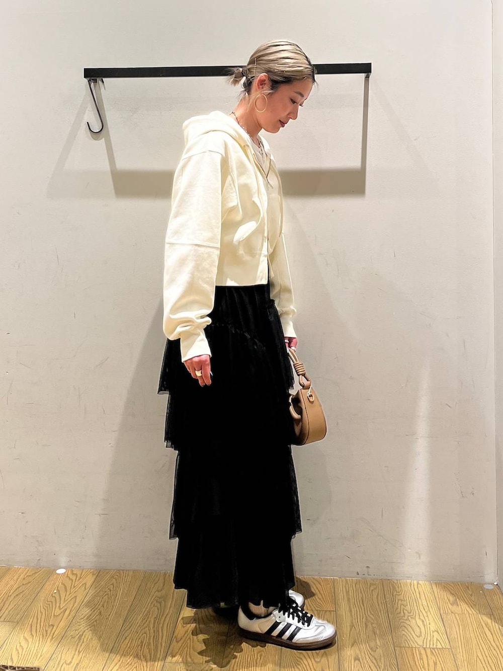 ベージュ系のハンドバッグ、ブラック系のスカート、ベージュ系のパーカーを着用したレディースの春コーディネートの3枚目の写真