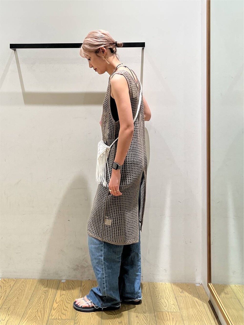ブルー系のデニムパンツ、ベージュ系のワンピース、ベージュ系のショルダーバッグを着用したレディースの夏コーディネートの3枚目の写真