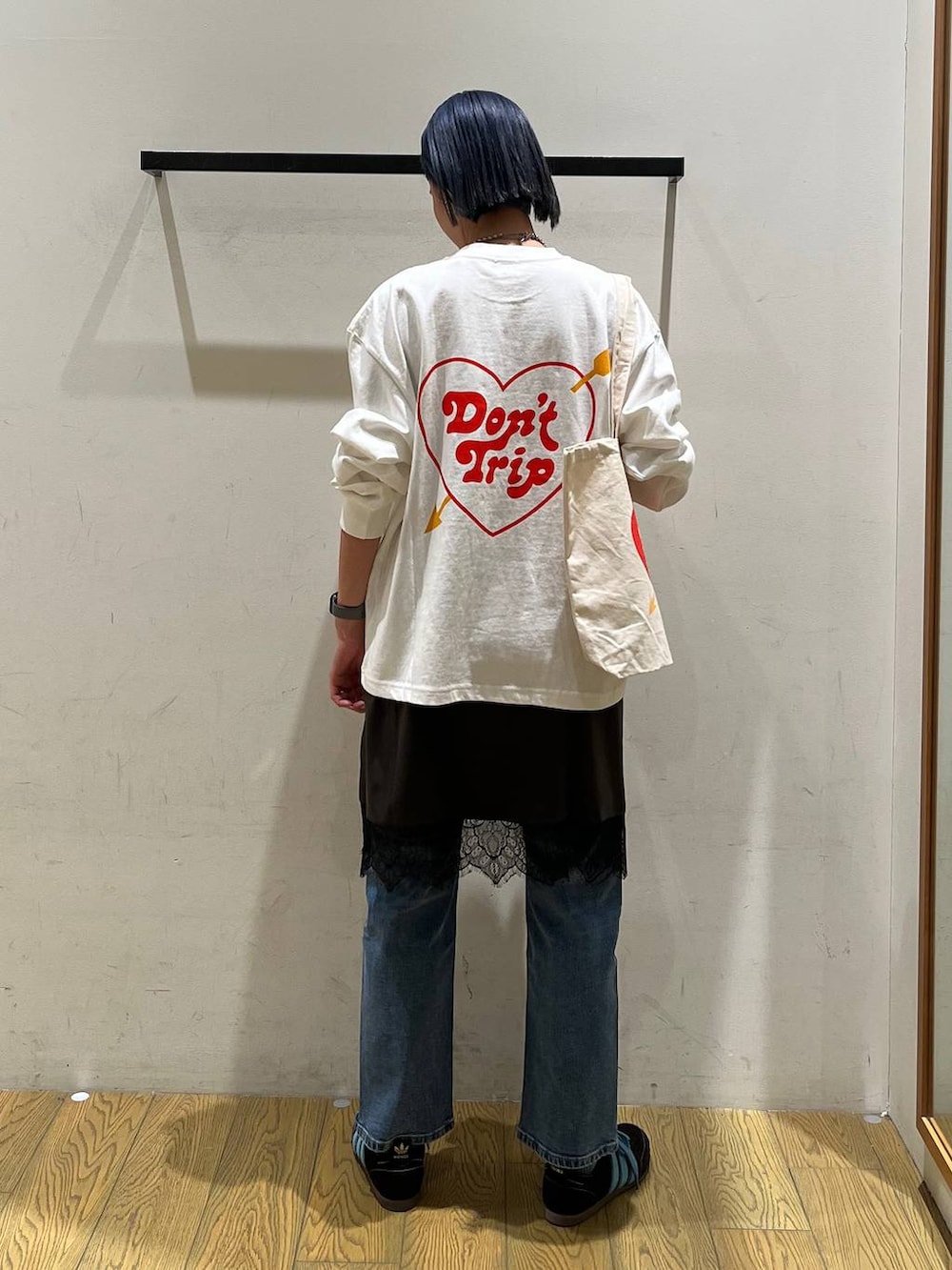 ブルー系のデニムパンツ、グレー系のワンピース、ベージュ系のトートバッグを着用したレディースの冬コーディネートの4枚目の写真