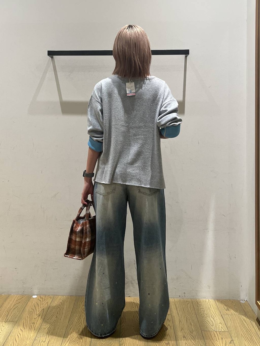 オレンジ系のトートバッグ、ブルー系のデニムパンツ、グレー系のニット/セーターを着用したレディースの秋コーディネートの4枚目の写真
