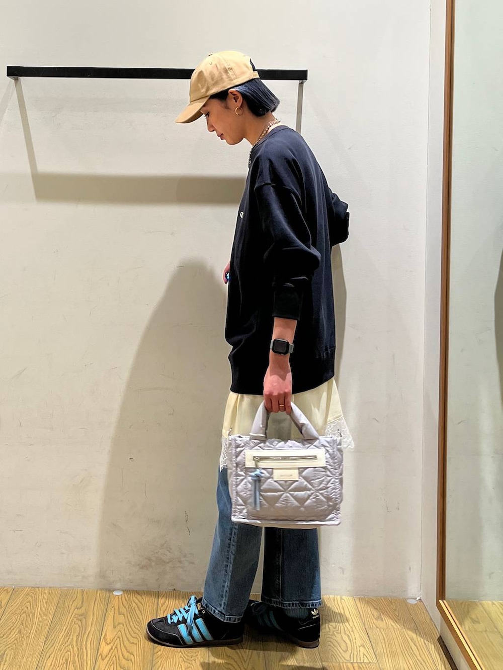 グレー系のショルダーバッグ、ブルー系のスウェット、ブルー系のデニムパンツを着用したレディースの冬コーディネートの2枚目の写真