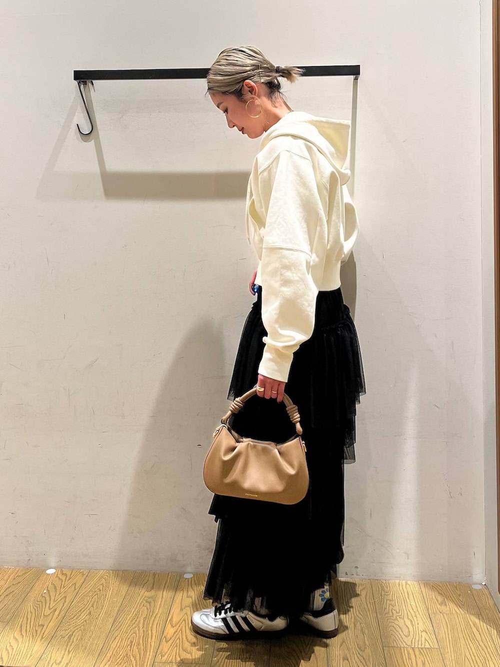 ベージュ系のハンドバッグ、ブラック系のスカート、ベージュ系のパーカーを着用したレディースの春コーディネートの2枚目の写真