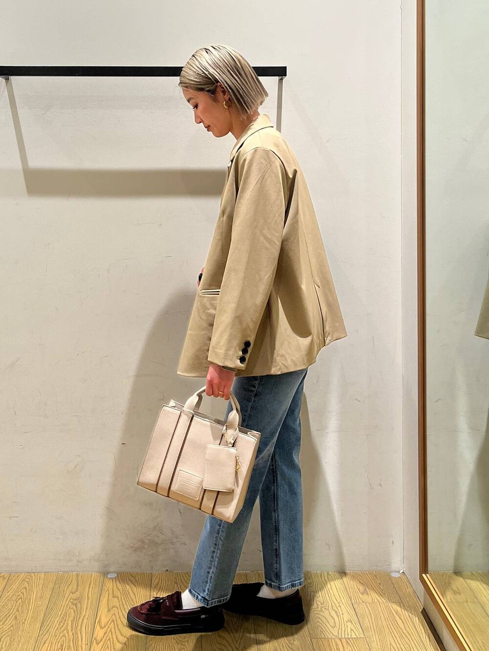 ベージュ系のハンドバッグ、ベージュ系のテーラードジャケット、ブルー系のデニムパンツを着用したレディースの冬コーディネートの3枚目の写真