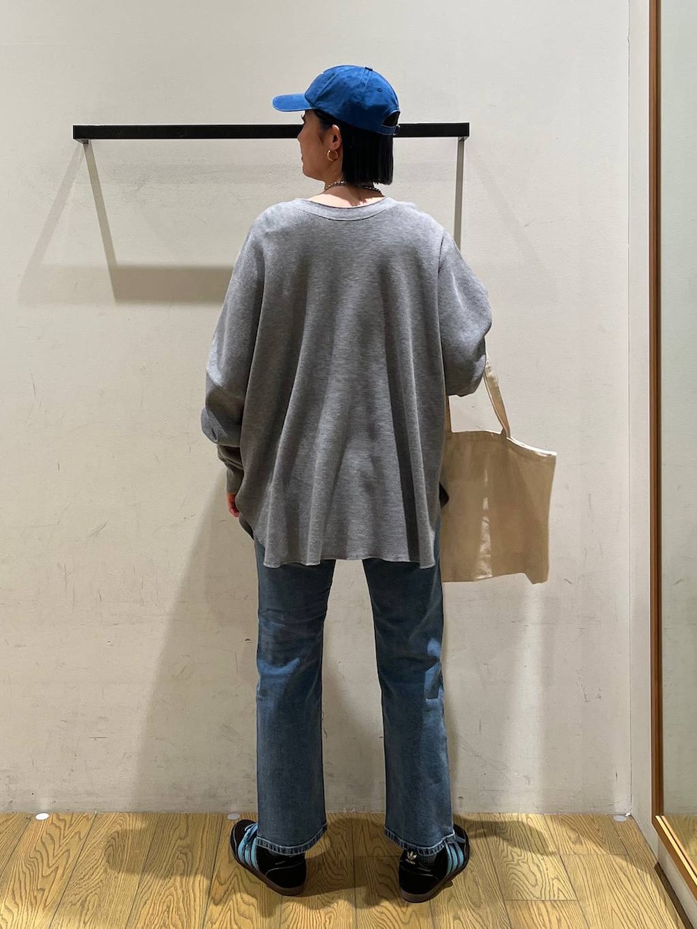 グレー系のカーディガン/ボレロ、ブルー系のデニムパンツ、ベージュ系のトートバッグを着用したレディースの冬コーディネートの4枚目の写真