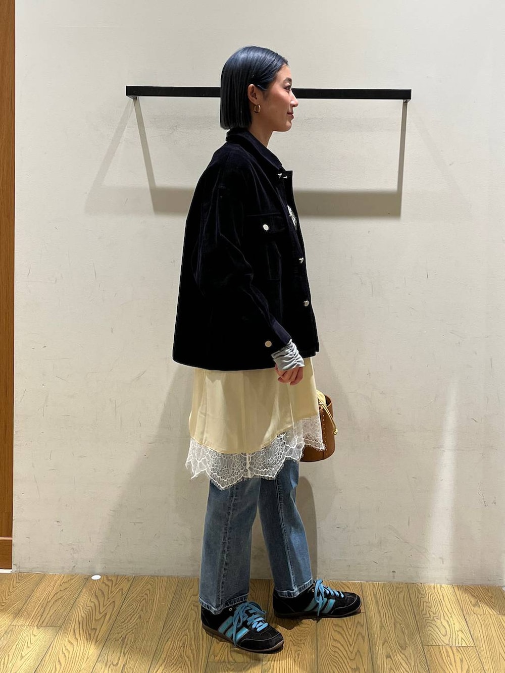 イエロー系のハンドバッグ、ブルー系のデニムパンツ、ベージュ系のワンピースを着用したレディースの冬コーディネートの3枚目の写真