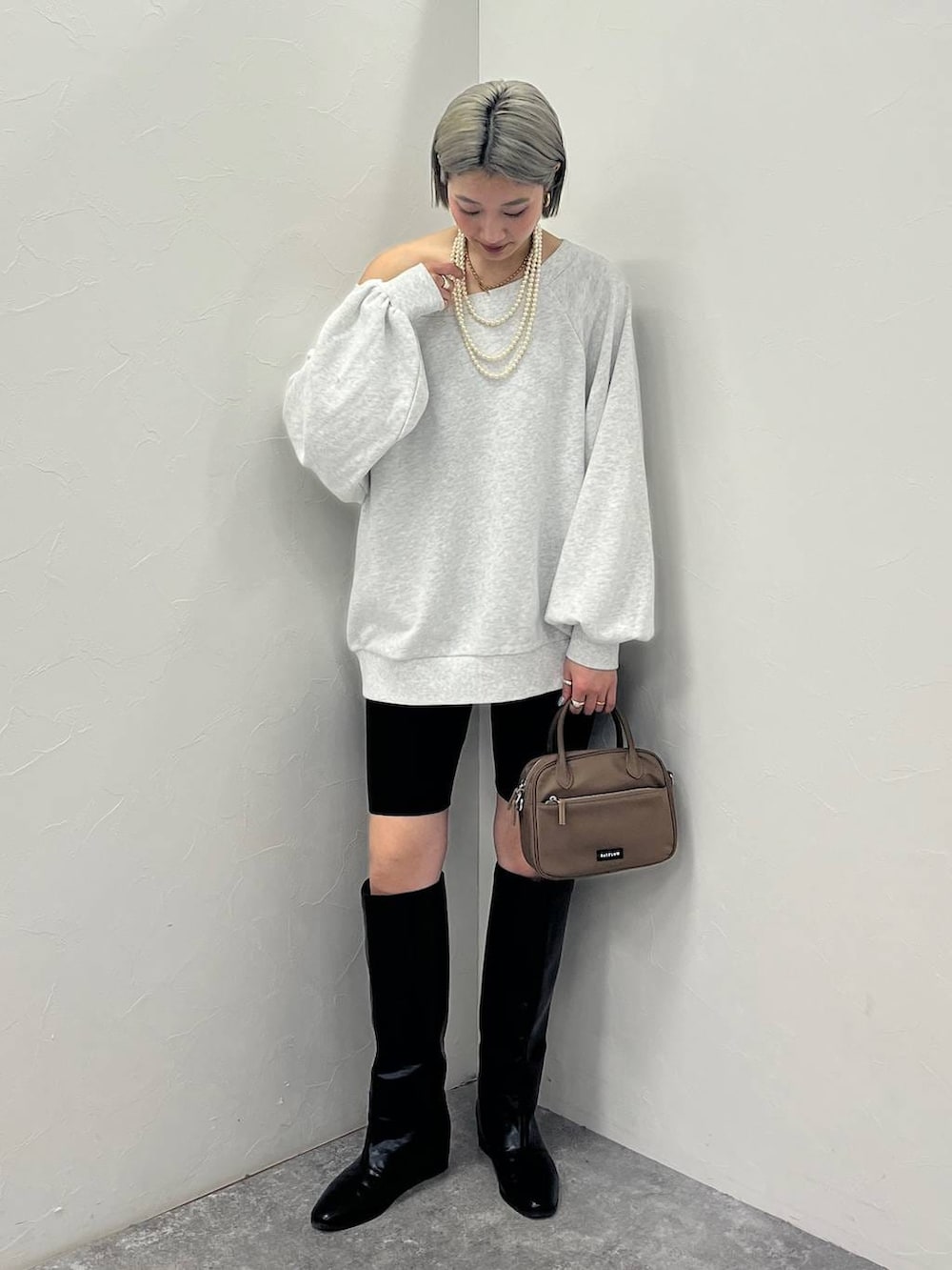 ブラック系のブーツ、ブラウン系のハンドバッグ、ブラック系のその他パンツを着用したレディースの冬コーディネートの2枚目の写真