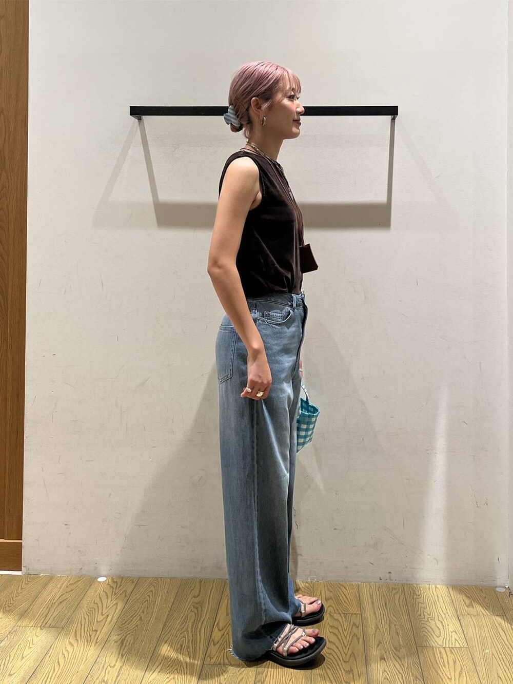 ブルー系のデニムパンツ、ブルー系のハンドバッグ、ブラウン系のネックレスを着用したレディースの夏コーディネートの2枚目の写真