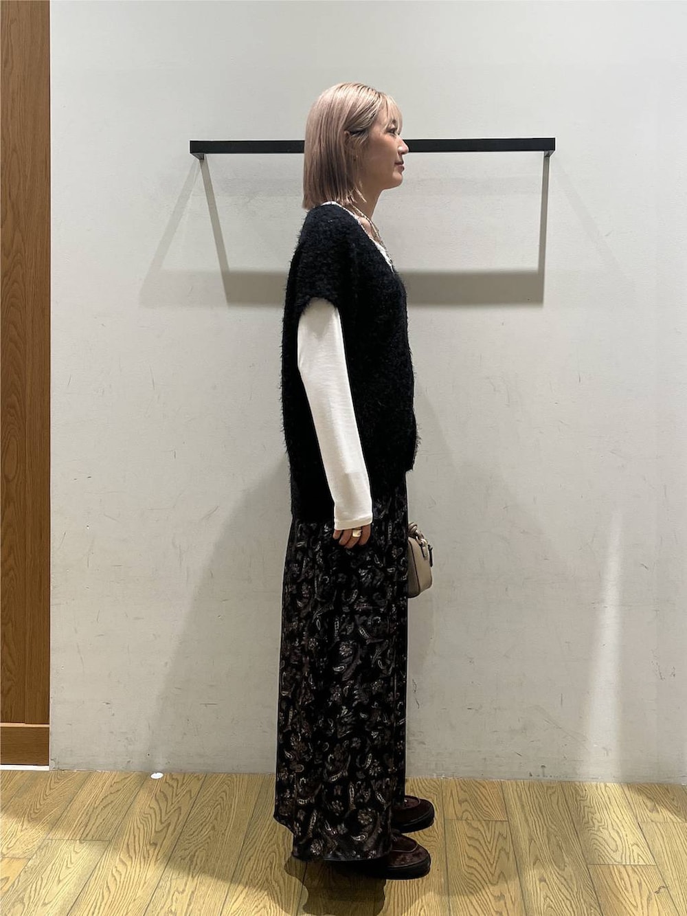 ブラック系のニット/セーター、ホワイト系のTシャツ/カットソー、ブルー系のスカートを着用したレディースの秋コーディネートの2枚目の写真