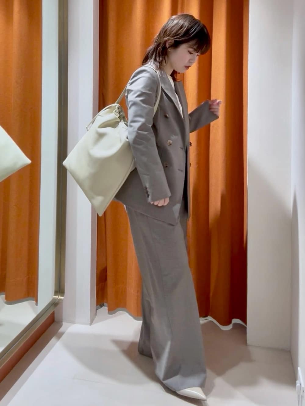 ホワイト系のシャツ/ブラウス、ブラウン系のスラックス、ホワイト系のショルダーバッグを着用したレディースの春コーディネートの2枚目の写真