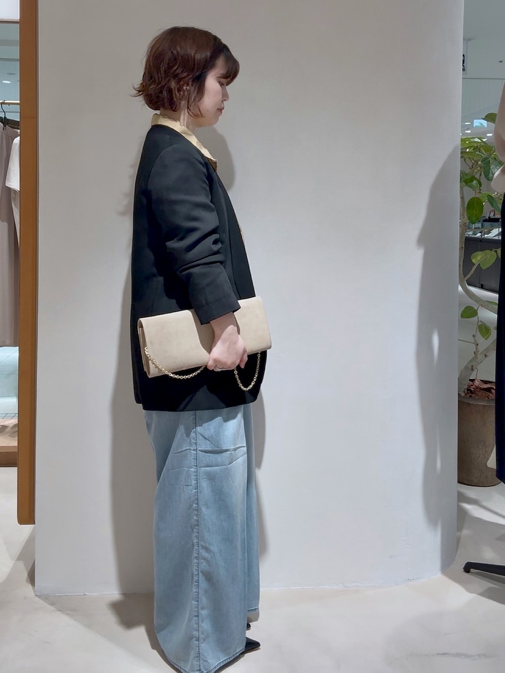ベージュ系のブルゾン、ブラック系のノーカラージャケット、ベージュ系のクラッチバッグを着用したレディースの夏コーディネートの2枚目の写真
