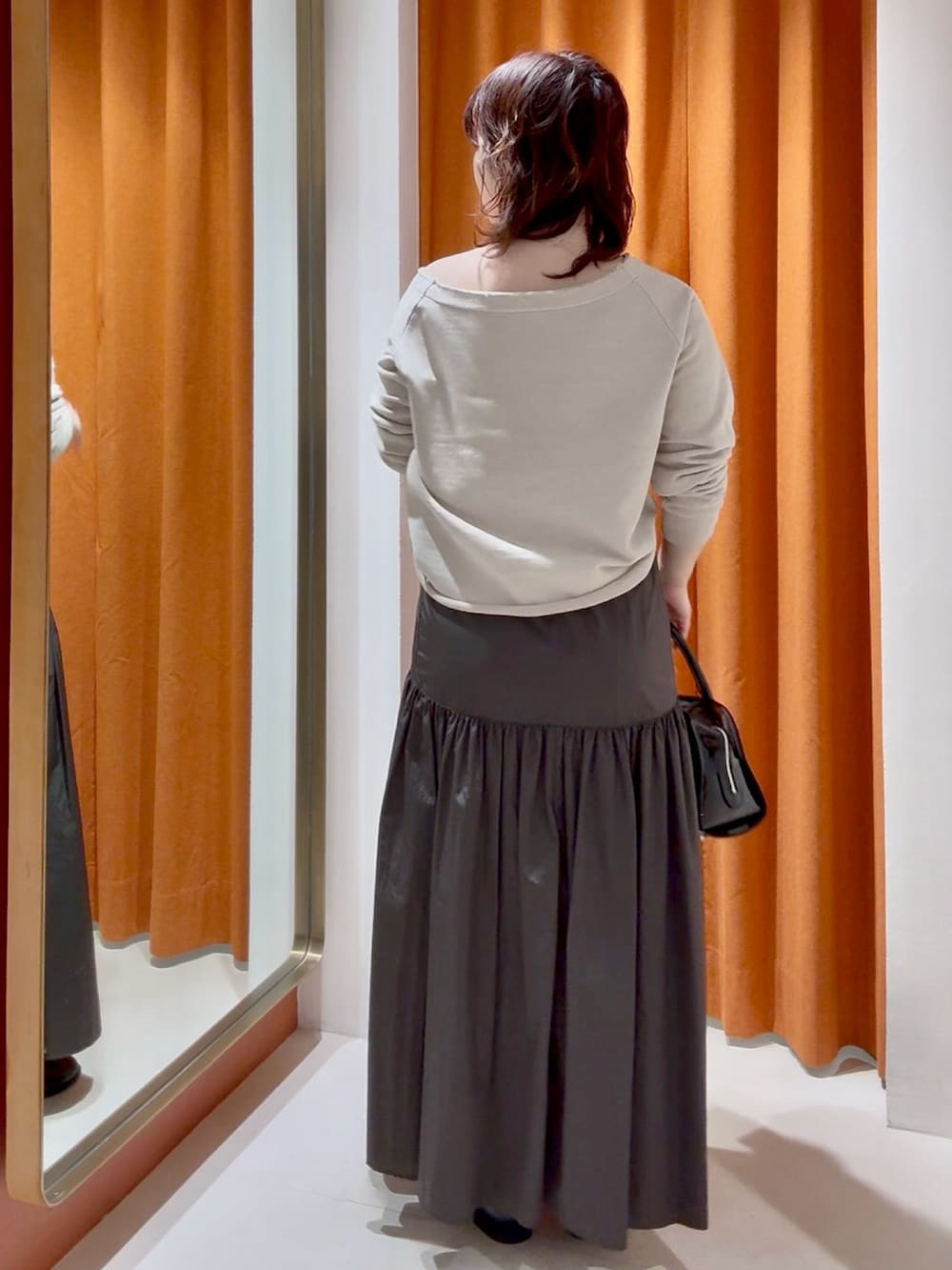 ブラウン系のスカート、ブラック系のボストンバッグ、ベージュ系のスウェットを着用したレディースの春コーディネートの3枚目の写真