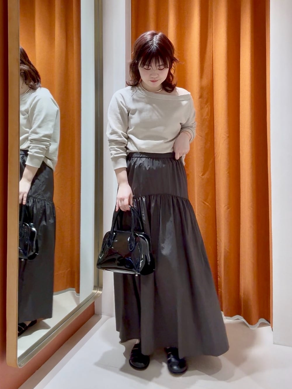 ブラウン系のスカート、ブラック系のボストンバッグ、ベージュ系のスウェットを着用したレディースの春コーディネートの4枚目の写真