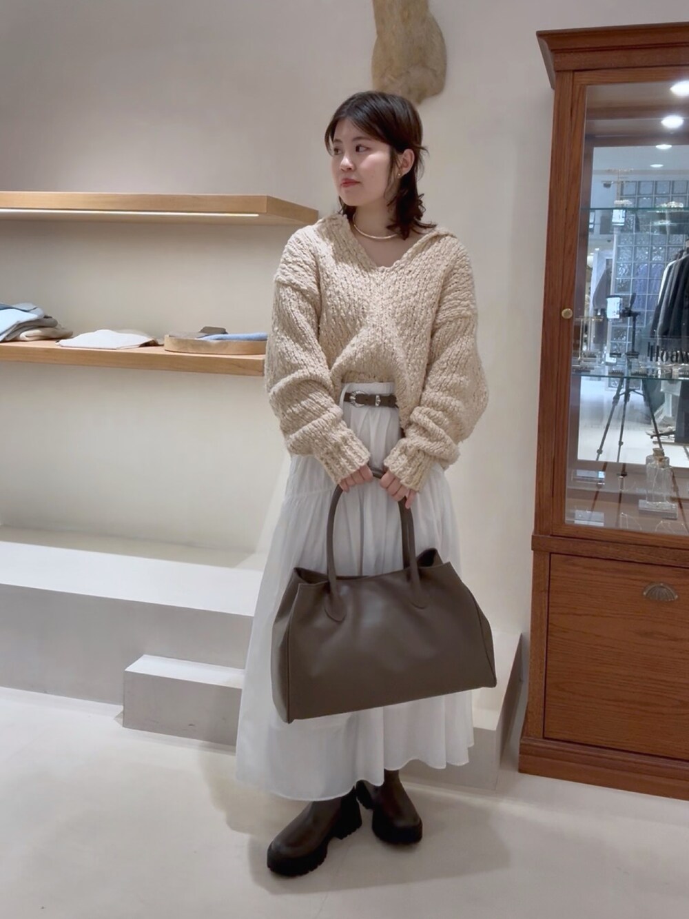 ベージュ系のニット/セーター、ホワイト系のスカート、グレー系のトートバッグを着用したレディースの冬コーディネートの5枚目の写真