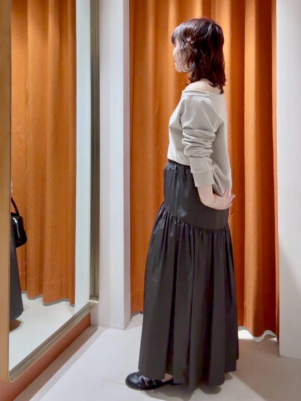 ブラウン系のスカート、ブラック系のボストンバッグ、ベージュ系のスウェットを着用したレディースの春コーディネートの2枚目の写真